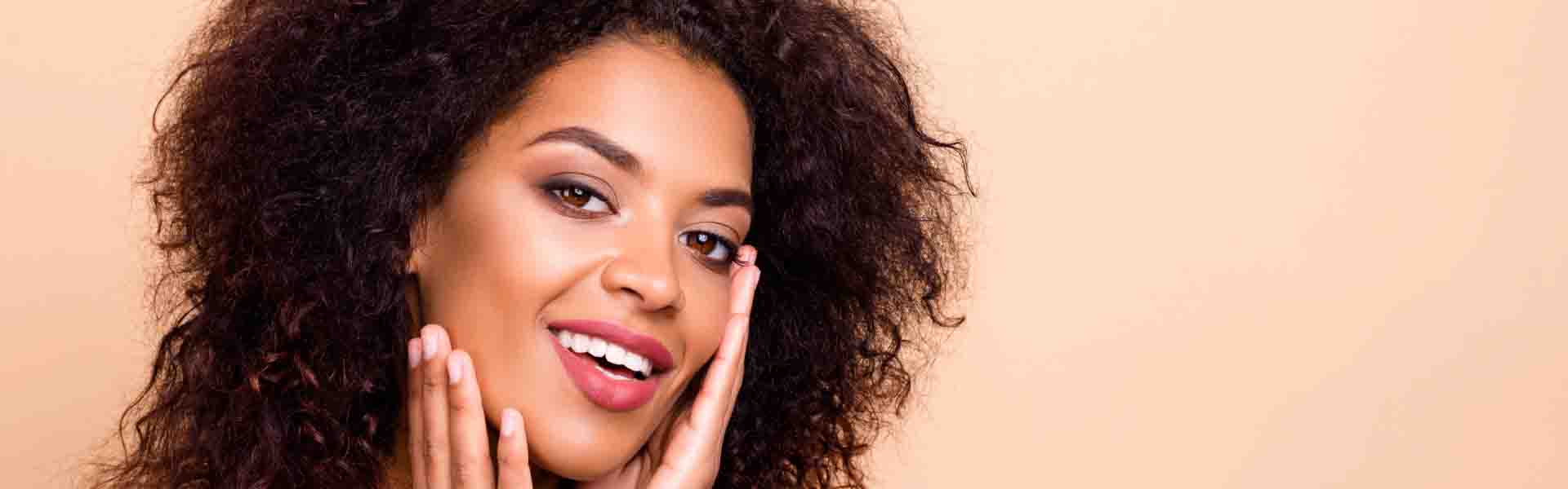 A smiling woman with curly hair showcases her cheerful demeanor, exuding warmth and happiness.