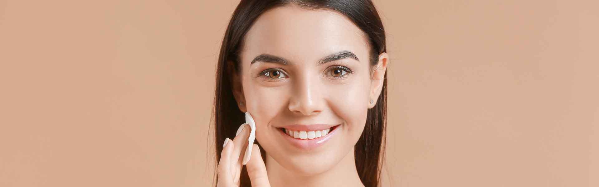 A woman smiles brightly while holding a white sponge in her hand, showcasing a cheerful and positive demeanor.