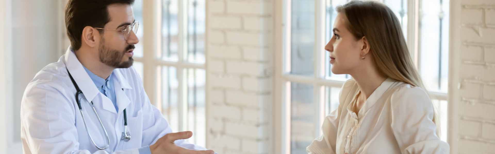 A doctor engages in conversation with a patient in a well-lit office setting, fostering a supportive environment.