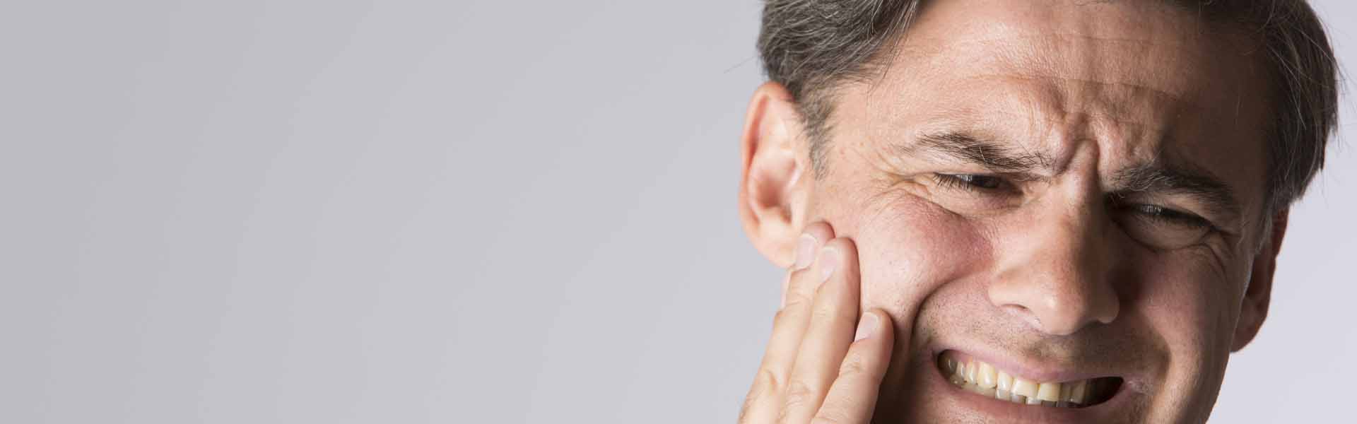 A distressed man clutches his face, clearly experiencing discomfort from a toothache.