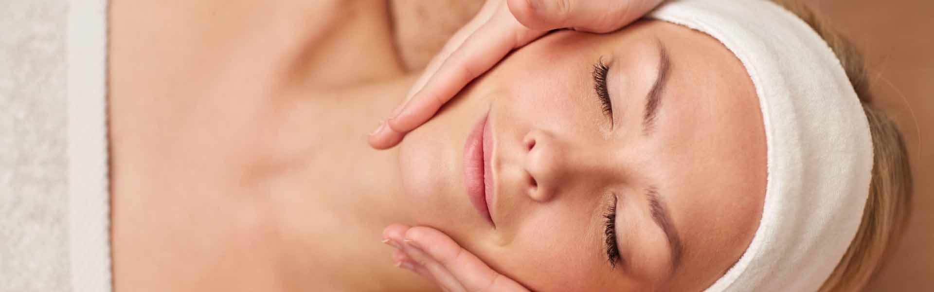 A woman enjoying a relaxing facial massage, her eyes closed and a serene expression on her face.